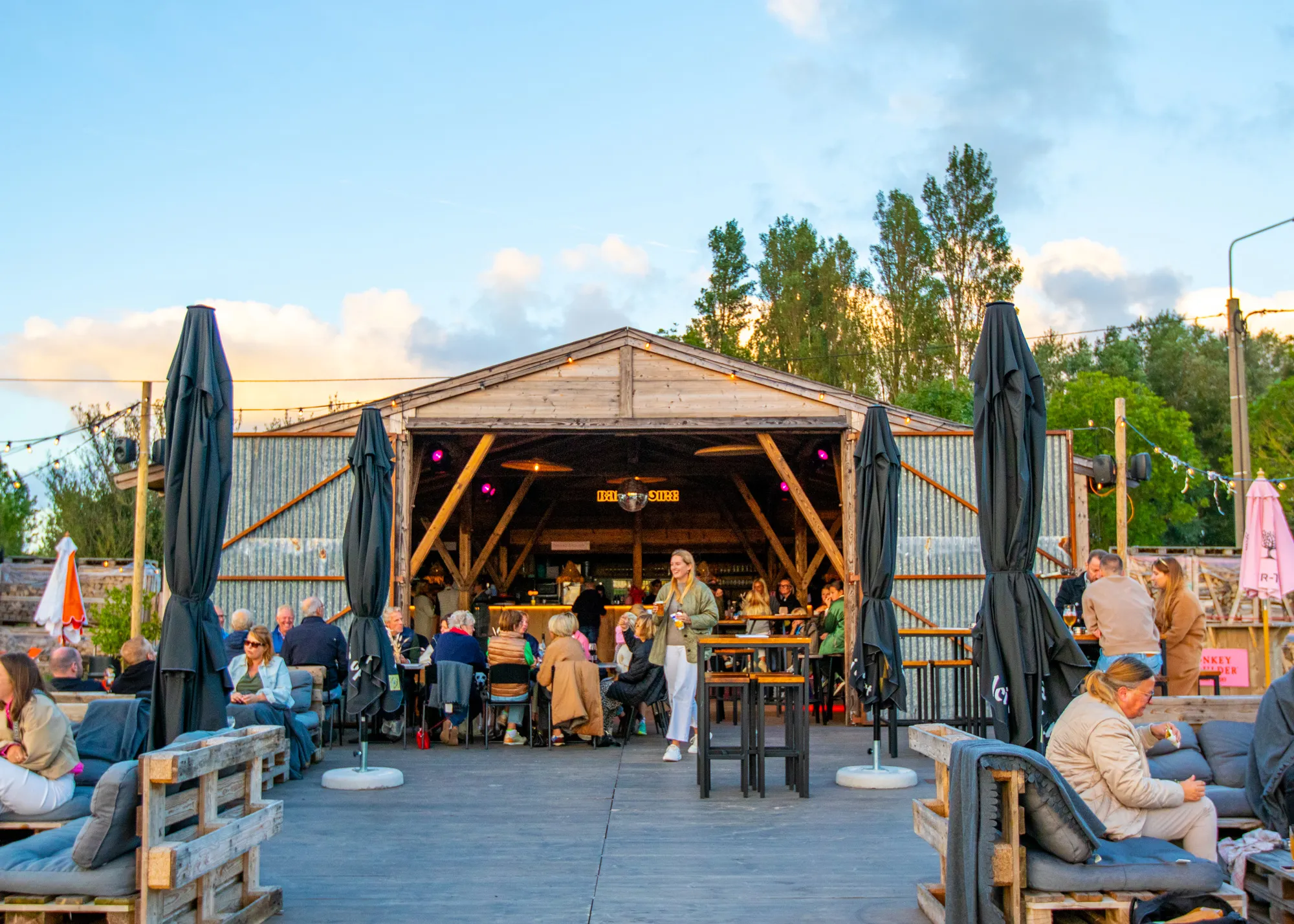 Exterior view of a luxury glamping bar with ambient lighting and seating