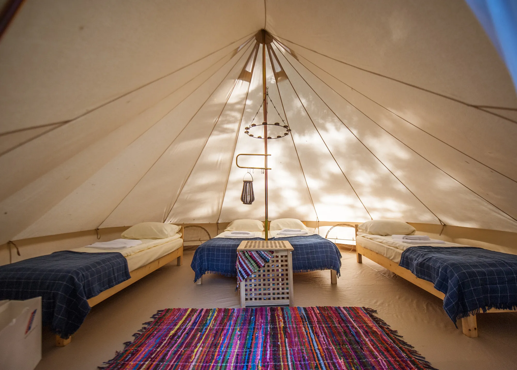 Interior of a luxury glamping tent with a double bed, bedside tables, and ambient lighting