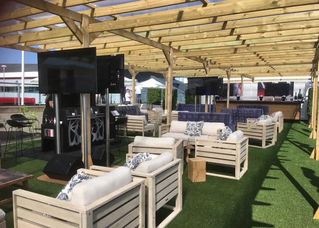 Wooden pergola interior with lounge seating, sofas, bar area and screens set up for a hospitality event