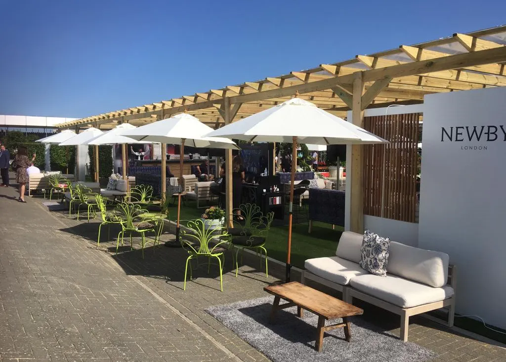 Outdoor timber pergola with seating, umbrellas and branded event setup along a walkway