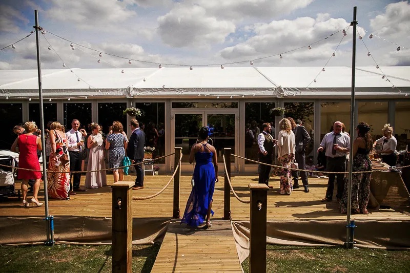 Open marquee interior with dancefloor and rustic bar area framed by trees