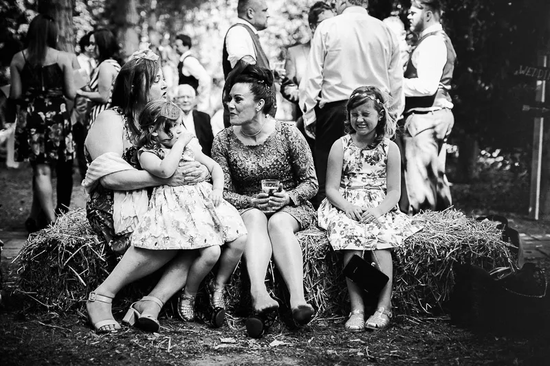 Bride and groom celebrating with guests outdoors beneath the trees