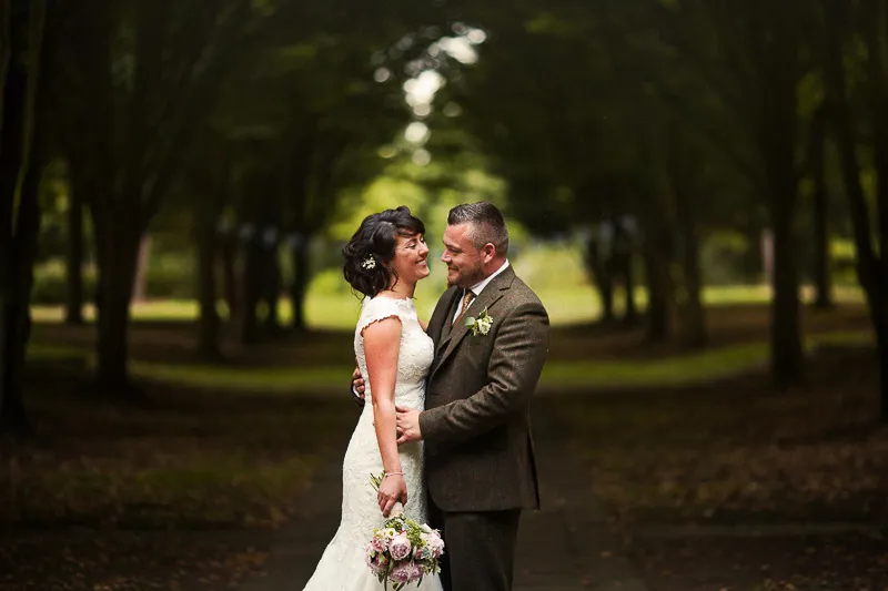 Bride and groom portrait beneath a tunnel of trees at The Tree Cathedral
